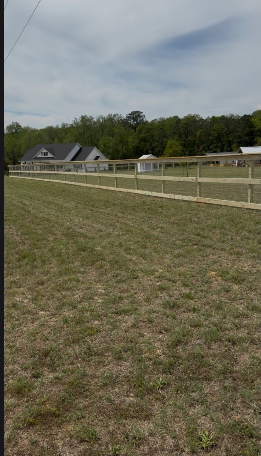 Long wood-and-wire fence installation around a large property